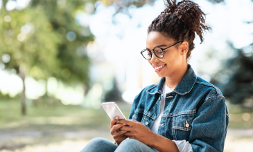 Young woman looks at her phone while outside